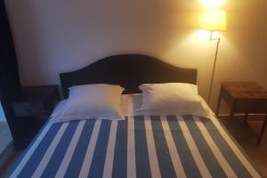 a bedroom with a bed with white pillows and a lamp at Pieds dans l'eau - La Villa Crique aux tortues in Zonza