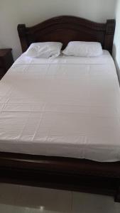 Una cama con sábanas blancas y dos almohadas. en Balcony Guatapé, en Guatapé