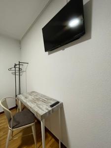 a table with a chair and a television on a wall at Pensión La Encina in Santo Domingo de la Calzada