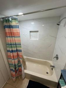 a bathroom with a tub and a shower curtain at 2 Bedroom Apartment By Airport in Hillside