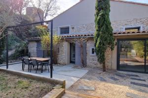 um pátio com uma mesa e cadeiras em frente a uma casa em La maison St Nicolas em Châteauneuf-du-Rhône