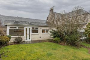 a house with a garage and a grass yard at The Tranquil Auchterarder 3-bed Cottage in Auchterarder