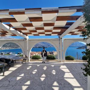 a woman walking under a pavilion with a view of the ocean at Apartmani Vila Marija in Budva