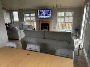 a living room with a couch and a flat screen tv at Millie,s View 18 hole free Golf in Swarland