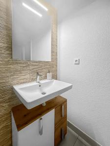 uma casa de banho com um lavatório branco e um espelho. em La Petite Pépite d'Ostwald em Ostwald