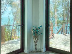 Un jarrón con flores al lado de una ventana en Ocean Shire home, en Alice Town