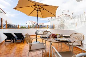 Un patio con una mesa y sillas y una sombrilla. en Apartment in the heart of Fañabe area, en Adeje
