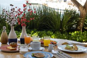 a table topped with plates of food and glasses of orange juice at Hotel Aretê in Búzios