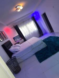 ein Schlafzimmer mit einem Bett und einem Fenster mit violetten Lichtern in der Unterkunft Joydora apartments 3 in Lusaka