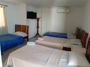 a room with three beds and a flat screen tv at Hotel Palma Real Cartagena in Cartagena de Indias