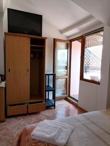 a bedroom with a flat screen tv on a wooden cabinet at Guesthouse Olimp in Sozopol