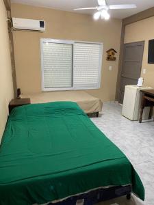 um quarto com uma cama verde e uma janela em LU DORMIS Alquiler Temporario em Corrientes