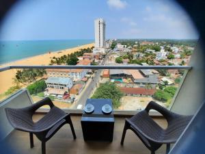 a balcony with chairs and a view of a beach at Ocean Breeze Aparthotel Negombo R11 B01 in Negombo