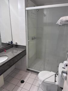 uma casa de banho com um chuveiro, um WC e um lavatório. em Charmoso Flat em frente ao Aeroporto de Congonhas em São Paulo