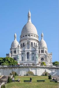 un gran edificio blanco con gente de pie en el césped en La parisienne, en Le Raincy