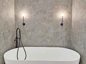 a bath tub in a bathroom with two lights on the wall at Shoreline - Emsworth in Emsworth