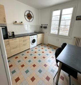 a kitchen with a washer and dryer on a tile floor at Au cœur des grattes ciels in Villeurbanne