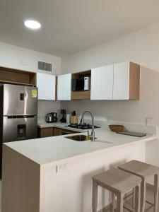 a kitchen with white cabinets and a counter with stools at Oasis Retreat - Cartagena in Los Arrayanes