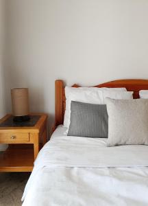 a white bed with a wooden headboard and a night stand at Vila Pašić in Igalo