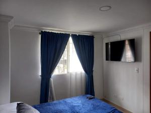 um quarto com uma cama e uma janela com cortinas azuis em APARTAESTUDIO DETRAS DE UNICENTRO em Armênia
