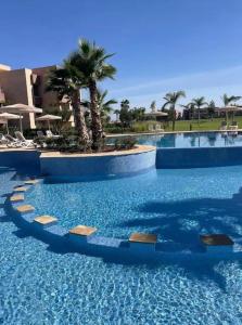 Una gran piscina con palmeras en un complejo turístico. en New appart, pool and golf view, en Marrakech