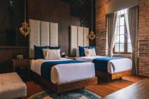 a bedroom with two beds with blue and white sheets at Hotel Cruz del Vado in Cuenca