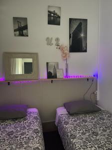 - 2 lits dans une chambre avec des lumières violettes dans l'établissement Glass Student-Übica2 Guesthouse, à Mairena del Aljarafe
