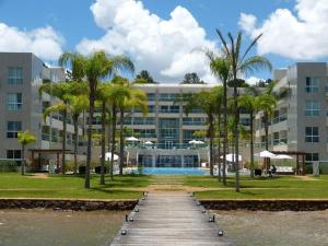 a building with a wooden walkway and palm trees in front at Brisas do Lago Diária Brasil 67961 in Brasilia