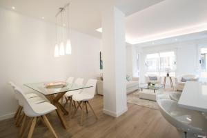 アリカンテにある4 bedroom/3 baths w/ AC in near beach!の白いダイニングルーム(ガラステーブル、白い椅子付)