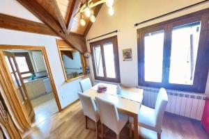 a dining room with a table and white chairs at Casa Ligües - tucasaenlospirineos in Escarrilla