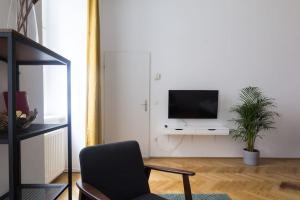 Una sala de estar con una silla y un televisor en la pared. en josef's home I Studio near City Center, en Viena