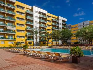 a hotel with a swimming pool and lounge chairs at Apartment Abora Garden with terrace, pool, extensive gardens and free parking in Las Palmas de Gran Canaria