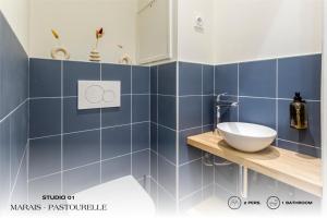 a bathroom with blue tiles and a sink on a counter at Beauquartier - Marais, Pastourelle in Paris