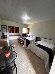 a hotel room with two beds and a table at Apt quarto 228 - hotel pedra Rodeadouro-Bonito-PE in Bonito