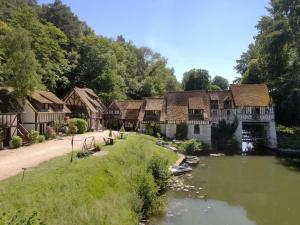 a group of buildings next to a river with boats at Le Moulin d'Andé in Andé