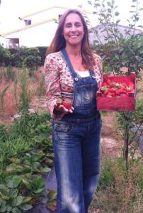 una mujer de pie en un jardín sosteniendo una caja de tomates en Casa do Vale-Villa with private pool and garden, en Palmela