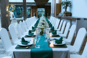池州市にあるJiuhua Mountain Demaotang Hotelの長テーブル(緑のナプキンと白い椅子付)