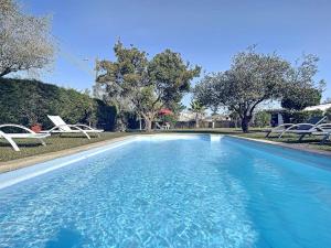 a swimming pool with two white chairs and trees at Casa do Vale-Villa with private pool and garden in Palmela