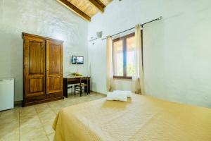 a bedroom with a bed and a desk and a window at Agriturismo Il Paradiso in Iglesias