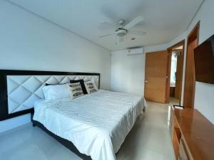 Schlafzimmer mit einem weißen Bett und einem Deckenventilator in der Unterkunft Lujosa Casa con jacuzzi CastilloGrande in Cartagena de Indias