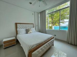 a bedroom with a bed and a large window at Lujosa Casa con jacuzzi CastilloGrande in Cartagena de Indias
