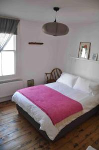 een slaapkamer met een groot bed en een paarse deken bij Lovely fisherman's cottage near beach and harbour in Whitstable