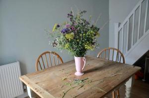 a vase of flowers sitting on top of a wooden table at Lovely fisherman's cottage near beach and harbour in Whitstable