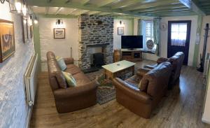 a living room with leather furniture and a fireplace at Ty Mawr at Bethania B&B in Llanon