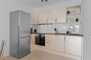 a kitchen with white cabinets and a stainless steel refrigerator at ☆Roomfall: Design Suite am Kurpark in Bad Rappenau