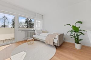 a living room with a white couch and a plant at ☆Roomfall: Design Suite am Kurpark in Bad Rappenau