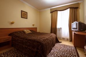 a hotel room with a bed and a television at Shato Leopard in Dombay