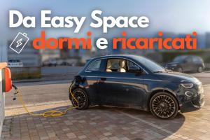 um pequeno carro azul está a ser cobrado numa rua em Easy Space em Bientina