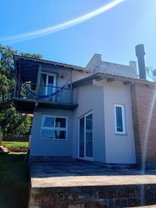 a white house with a balcony on top of it at Chalé em Torres Recanto Estelar in Torres