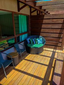 a porch with a bed and two chairs on a deck at Reserva dos Carneiros - Flat-Apartamento em Carneiros in Tamandaré